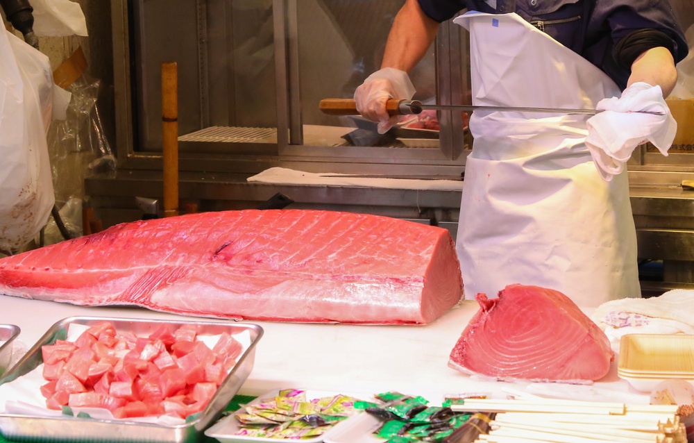 The fishmonger cleaning his knife to prepared for cut the big tuna into pieces